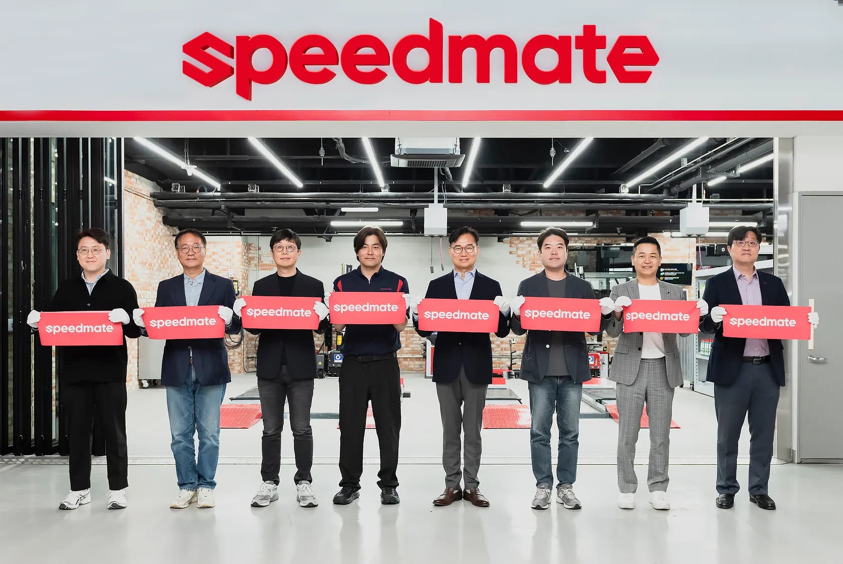 스피드메이트 강동아이파크점에서 신규 로고와 함께 기념사진을 촬영하고 있는 안무인 SK스피드메이트 대표(오른쪽 네번째) 등 사업부서 관계자들의 모습